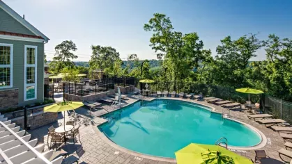 Scenic poolside view with a backdrop of rolling green hills, providing a peaceful oasis for residents to enjoy a refreshing swim.