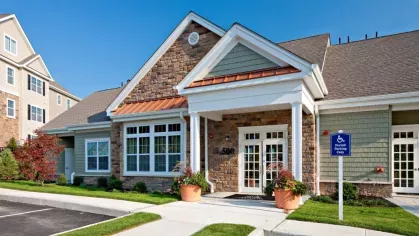 The welcoming leasing office at Vista At Town Green, showcasing classic stone and siding architecture with beautifully maintained landscaping.