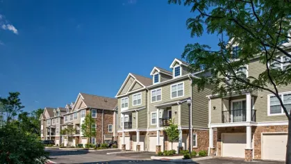 A row of upscale townhomes with private balconies and garages, showcasing the stylish architecture of Vista At Town Green Luxury Apartments.