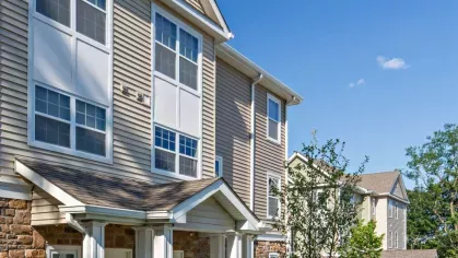 Close-up of the sophisticated townhome exterior, featuring large windows, neutral-toned siding, and classic stone details.