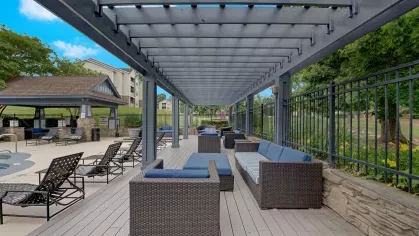 A shaded pergola with wicker seating and blue cushions near the pool area.
