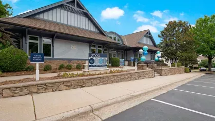 7029 West Apartments leasing office with stone accents, blue and white balloons, and clear signage welcoming future residents.