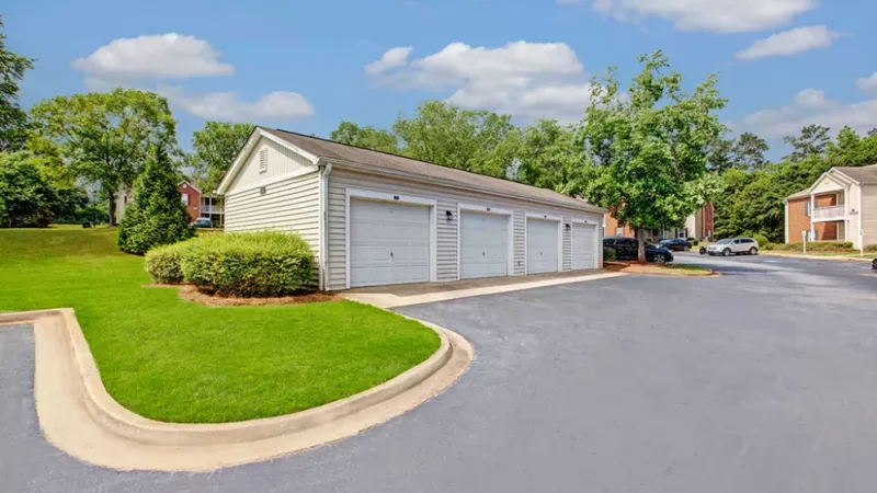Detached garage building with white siding and multiple single-car garages in a landscaped community.