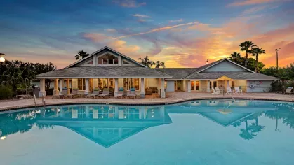 Beautiful clubhouse with large windows and a relaxing pool area at sunset, offering a welcoming ambiance.