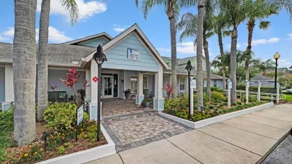 Inviting entrance to the Abaco Key clubhouse, featuring tropical landscaping, palm trees, and a welcoming porch.