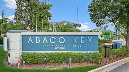 Abaco Key luxury apartment homes sign with a vibrant blue backdrop and surrounding greenery.
