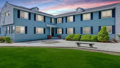 Another angle of the blue multi-unit apartment building at Alcove at Seahurst, showcasing greenery and a serene environment.