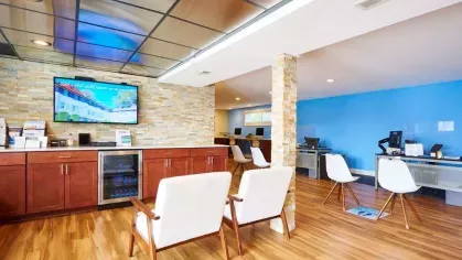 Welcoming office space with contemporary seating, a stone accent wall, and a bright blue backdrop at Alcove at Seahurst.