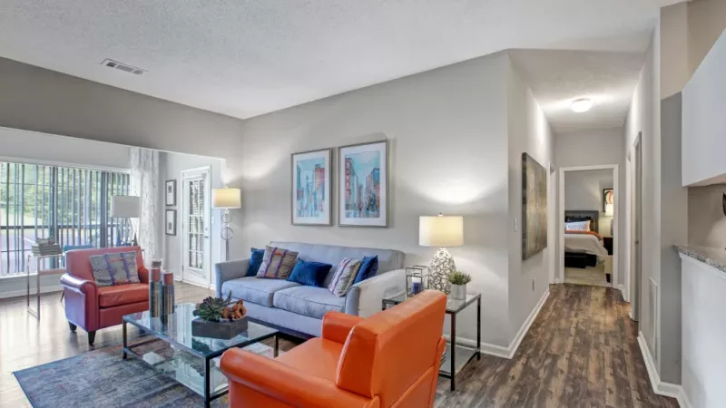 Bright and inviting living room with orange armchairs, a gray sofa, and modern decor in an open-concept apartment.
