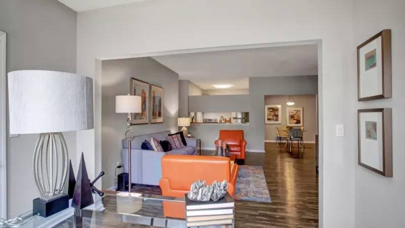 View of a stylish living room leading into the dining area, featuring modern furniture and vibrant accents.