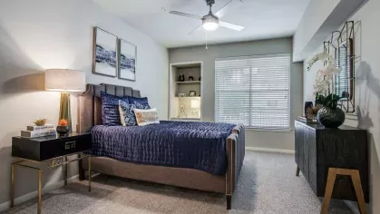 A luxurious master bedroom with a king-size bed, built-in shelving, and modern decor under soft lighting.