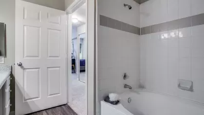 A master bathroom with a wide mirror, modern lighting fixtures, and ample counter space.