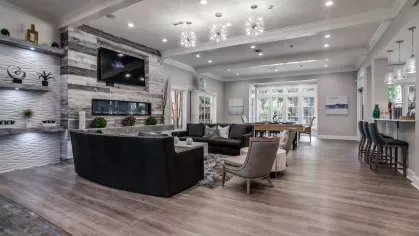 A spacious and elegant lounge with natural light, modern furnishings, and a view of the outdoor pool.