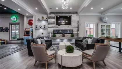 A spacious and elegant lounge with natural light, modern furnishings, and a view of the outdoor pool.