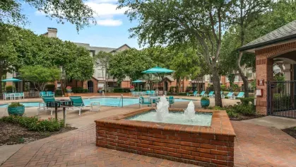 A serene courtyard with a bubbling fountain, landscaped pathways, and views of the swimming pool.