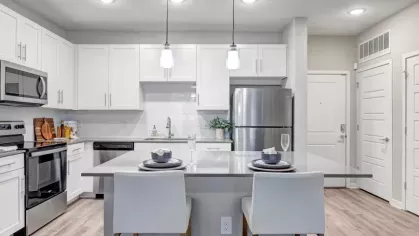 A contemporary kitchen with a bright, open layout, white cabinets, and a gray countertop island with seating.