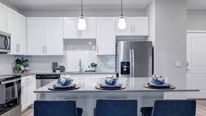 A modern open-concept kitchen with an extended island, pendant lighting, and a connected living space in neutral tones.