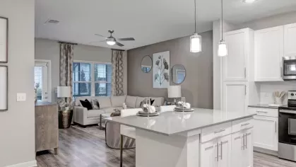 A chic kitchen with a gray island, three dark barstools, and a bright, inviting atmosphere.