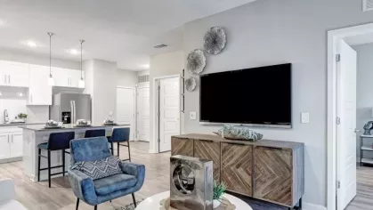 A cozy living area with a sectional sofa, coffee table, and an open view of the modern kitchen.