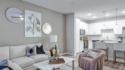 A stylish living space with a white couch, blue accent chairs, and a kitchen in the background, creating a seamless layout.