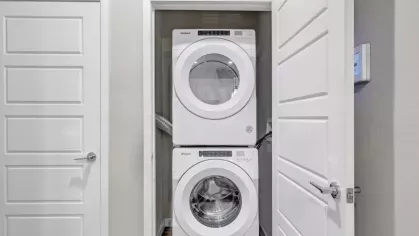 A compact laundry space featuring a stacked Whirlpool washer and dryer behind a white door.