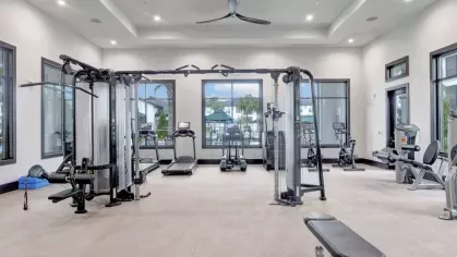 A spacious fitness center with a variety of weight machines, treadmills, and large windows bringing in natural light.