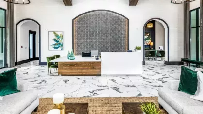 A stylish leasing office with marble flooring, modern chandeliers, and a sleek reception desk with decorative accents.