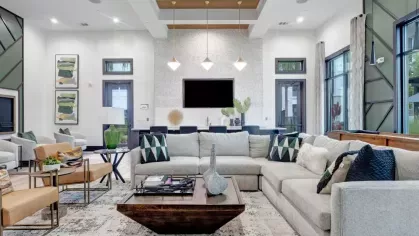 A contemporary clubhouse lounge with a sectional sofa, accent chairs, and pendant lighting creating a cozy yet sophisticated atmosphere.