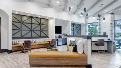 A spacious common area with sleek seating, geometric wall panels, and a coffee station, offering a welcoming gathering space.