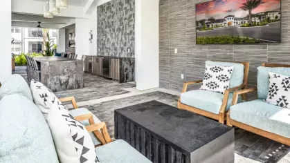 An upscale outdoor lounge area with cushioned chairs, a mounted TV, and a built-in bar, perfect for entertaining.