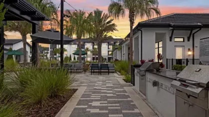 A relaxing outdoor space with a sunset sky, stylish lounge chairs, and a pristine swimming pool.