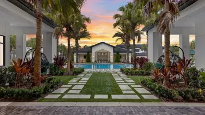 A beautifully landscaped outdoor grilling and dining area, illuminated by the warm glow of sunset.