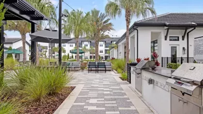 A modern outdoor grilling station and dining area surrounded by lush greenery.