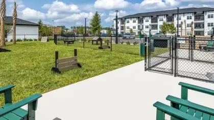 A dog-friendly park with fenced-in areas, green seating, and agility obstacles.