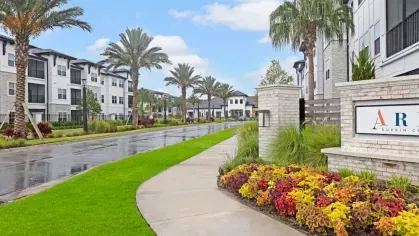 A gated entrance to a pet park, featuring seating and a view of apartment buildings.
