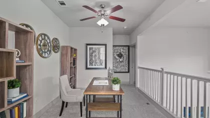 A bright office space with a ceiling fan, wooden shelves, and a desk, perfect for remote work at Arrabella Apartments.