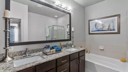 Elegant master bathroom featuring dual granite countertops, a soaking tub, and sleek modern fixtures.