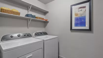 Spacious in-unit laundry room featuring modern Whirlpool washer and dryer with additional shelving for storage and organization.