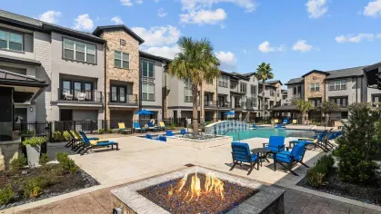 A cozy outdoor fire pit with modern seating, adjacent to the pool area, creating a perfect evening ambiance.