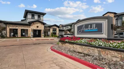 Beautifully designed leasing office with a stone facade, landscaped flower beds, and accessible parking.