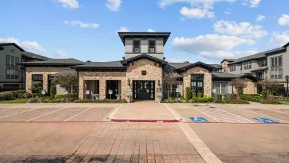 Beautifully designed leasing office with a stone facade, landscaped flower beds, and accessible parking.