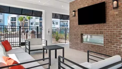 Outdoor lounge area with modern seating, a fire pit, and views of the pool and surrounding apartment buildings at Array Vista Canyon Apartments.