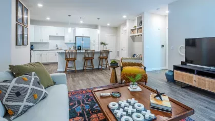 A beautifully decorated living room with a neutral sofa, patterned throw pillows, and a statement coffee table, complemented by a textured area rug.