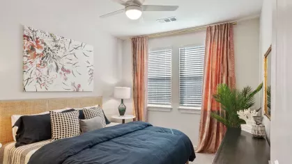 Luxurious bedroom with a modern ceiling fan, stylish bedding, and large windows allowing for natural light.