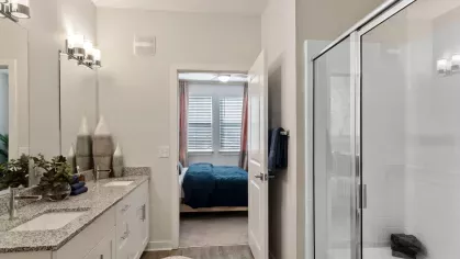 Modern bathroom with a granite vanity, stylish lighting, and a full-size bathtub with a shower.