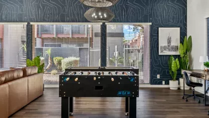 Game room featuring a foosball table, leather seating, and a vibrant blue accent wall with modern decor.
