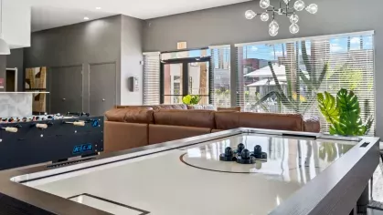 Air hockey table in a bright and modern game room with large windows and comfortable seating.