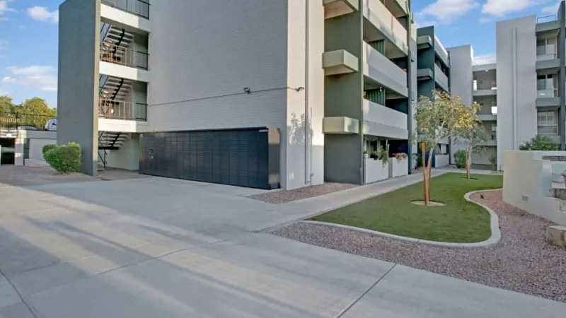 Contemporary apartment exterior with clean lines, modern gray and white tones, and a small landscaped courtyard.