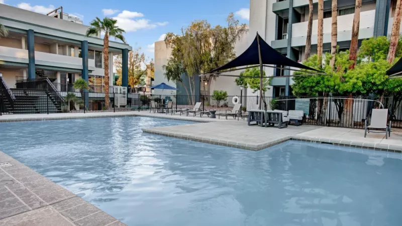 Large swimming pool with shallow entry, surrounded by comfortable lounge seating and shaded areas.