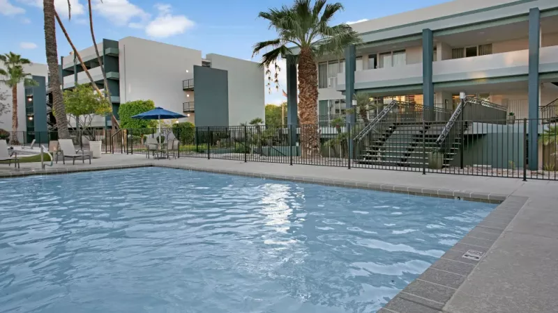 Modern apartment pool area with a serene water feature, stylish seating, and contemporary architecture.